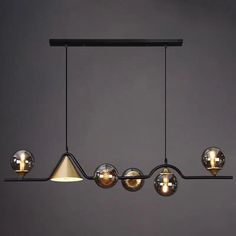 a modern light fixture hanging from the ceiling with three lights on each side and four different shades