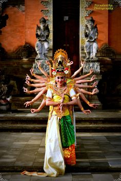 a woman dressed in an elaborate costume with her arms spread out and hands extended up