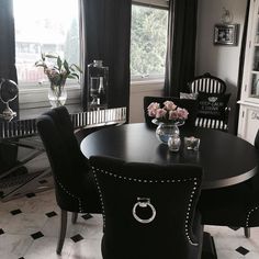 a black and white dining room with flowers in vases on the table, chairs around it