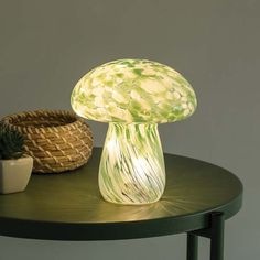 an illuminated mushroom lamp sitting on top of a table next to a potted plant