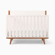 a white crib with wooden legs and no sheets on the bottom, against a white background