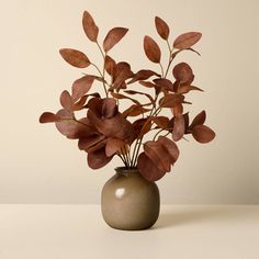 a vase filled with red leaves on top of a table