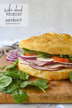 a sandwich with meat and vegetables on a cutting board