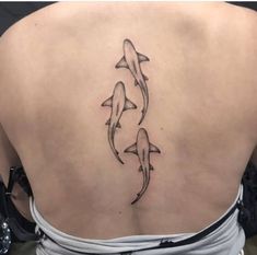 a woman's back with three dolphins tattoo on her left side ribcage