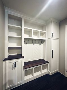 an empty room with white cabinets and black counter tops on the wall, along with wooden flooring