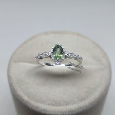 a ring with a green stone in it sitting on top of a white display case