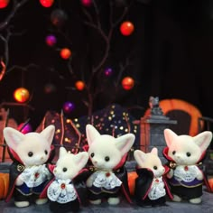 three little mice dressed up in halloween costumes, standing next to each other with pumpkins behind them