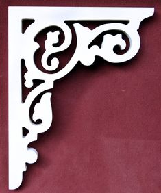 an ornate white shelf bracket on a red wall