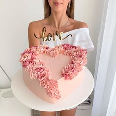 a woman holding a heart shaped cake with the word hope spelled on it