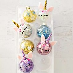 unicorn ornament ornaments with glitter on them in a plastic container, sitting on a white surface