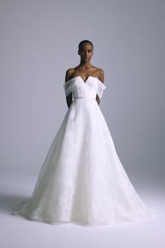 a woman in a white wedding dress posing for the camera with her hands on her hips