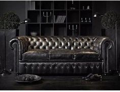 a black leather couch sitting in front of a book shelf