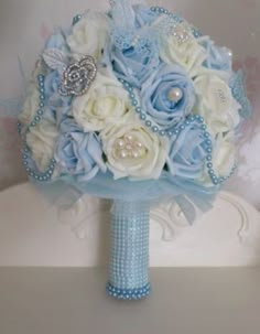 a bridal bouquet with blue and white flowers on a table in front of a wall