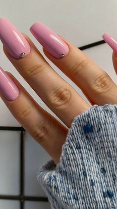 a woman's hand with pink nail polish on it and a blue sweater in the background