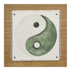 a green and white painting with two black dots on the yin yang symbol, in front of a wooden background