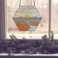 a stained glass window with pine cones and evergreens on the windowsill in front of it