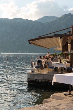 people are sitting at tables near the water