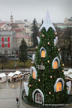 a large christmas tree in the middle of a plaza with lights and decorations on it