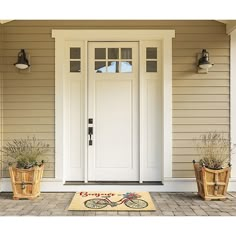 two planters with plants are sitting in front of a white door on the side of a house