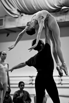 two people doing acrobatic tricks in front of a group of people watching