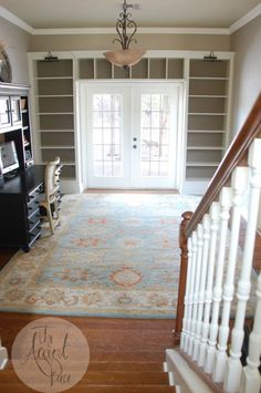 a living room with stairs leading up to the front door and an area rug on the floor