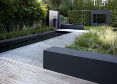 an outdoor garden with wooden decking and plants on the wall, surrounded by greenery