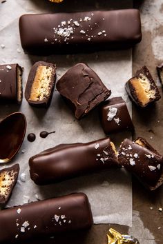 several pieces of chocolate covered dessert sitting on top of a piece of parchment paper next to spoons