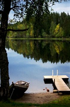 two boats are docked on the shore of a lake