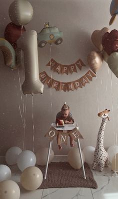 a child's first birthday party with balloons, giraffes and decorations