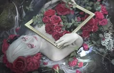 a mannequin is surrounded by flowers and framed with a gold frame in the middle