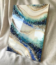 a blue and white art piece sitting on top of a bed