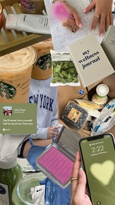 a person holding a cell phone in front of a pile of books and other items