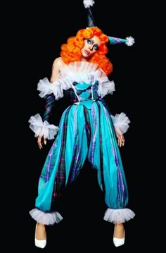 an orange haired woman dressed in blue and green clothing with white ruffles on her legs