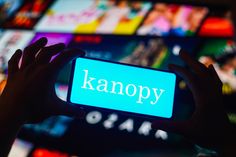 a person holding up a smart phone with the word kanopy on it's screen