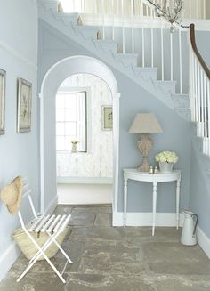 a white table sitting under a stair case next to a blue painted wall in a living room