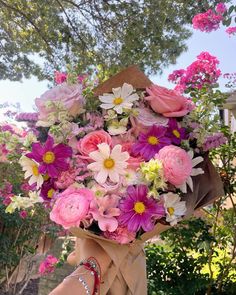 a woman holding a large bouquet of flowers in her right hand and wearing a bracelet