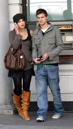 a man and woman standing next to each other talking on their cell phones in front of an atm