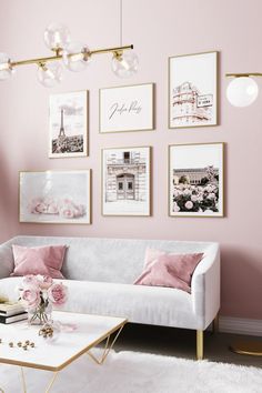 a living room with pink walls and pictures on the wall above the white couches