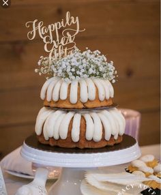 a three tiered cake with white frosting and flowers on top is sitting on a table