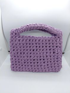 a purple crocheted purse sitting on top of a white chair