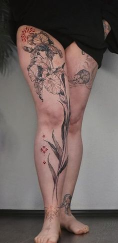 a woman's legs with tattoos on them and flowers in the bottom right leg