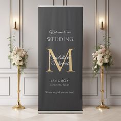 a black and gold wedding sign with flowers in vases on the floor next to it