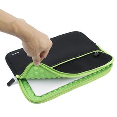 a hand is pointing at a green and black laptop case that has a white pad on it