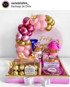 a pink and gold birthday gift basket with balloons