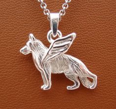 a silver pendant with a dog on it's back and wings in the shape of an angel