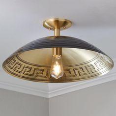 a light fixture in a room with white walls and gold trimmings on the ceiling