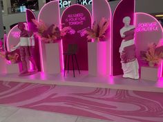 a display with pink lighting and flowers in front of a woman's dress on the mannequins