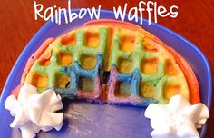 a blue plate topped with waffles covered in frosting and rainbow toppings