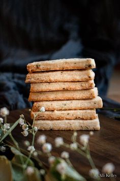 a stack of crackers sitting on top of a wooden table next to some flowers