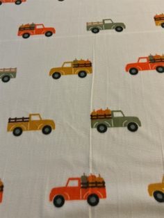 a white sheet with orange and green trucks on it